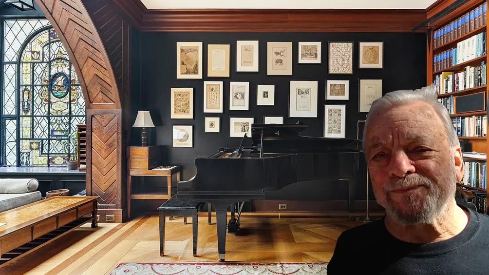 Stephen Sondheim against backdrop of his piano and pictures from his works