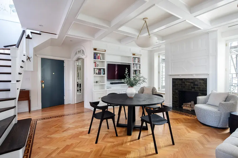 Dining area with fireplace, coffered ceiling, and staircase