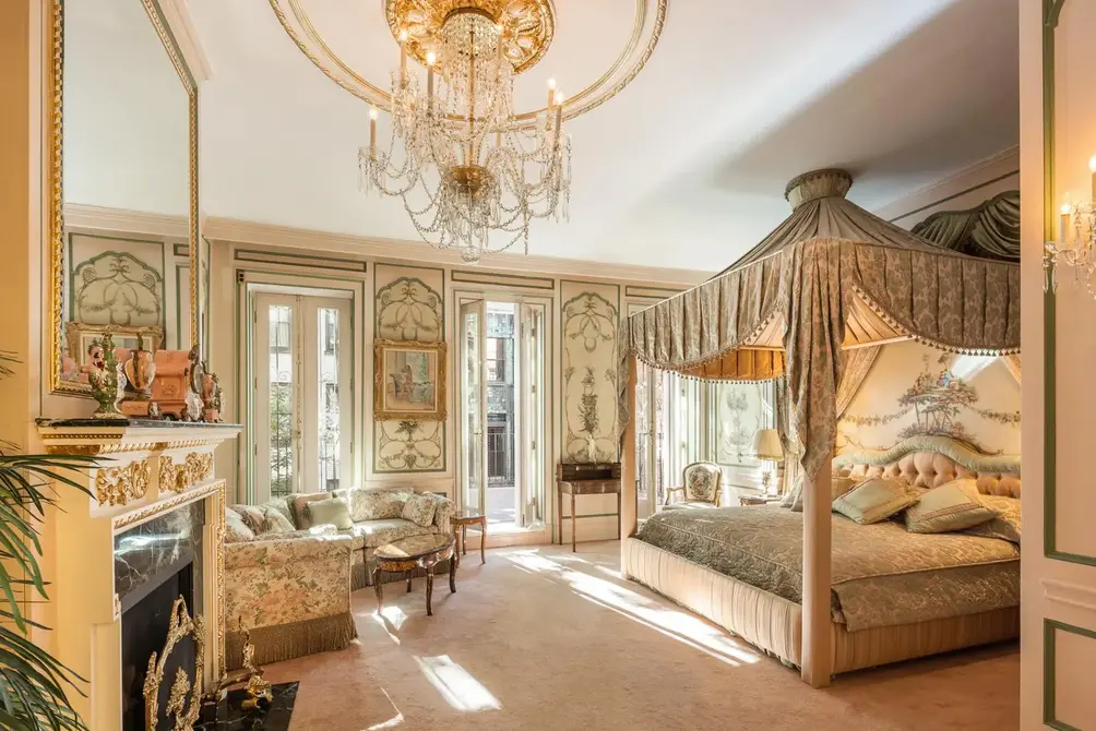 Bedroom with crystal chandelier and gold-trimmed fireplace